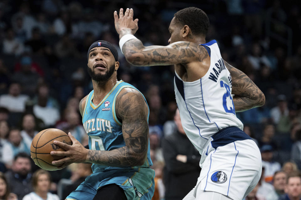 Dallas Mavericks forward P.J. Washington (25) guards Charlotte Hornets forward Miles Bridges (0) during the first half of an NBA basketball game Tuesday, April 9, 2024, in Charlotte, N.C. (AP Photo/Jacob Kupferman)