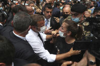 French President Emmanuel Macron, speaks with a woman as he visits the Gemayzeh neighborhood, which suffered extensive damage from an explosion on Tuesday that hit the seaport of Beirut, Lebanon, Thursday, Aug. 6, 2020. (AP Photo/Bilal Hussein)