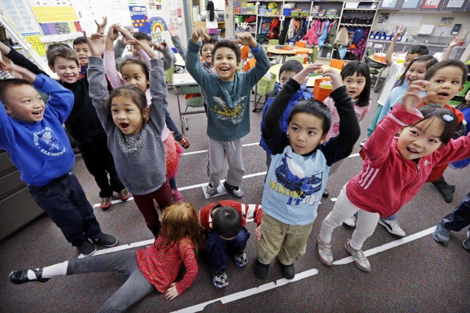 In this photo taken Friday, Feb. 14, 2014, kindergarten students in a dual immersion language class leap to their feet as they repeat a word for "stand" said in Vietnamese back to their teacher at White Center Heights Elementary School in Seattle. In a handful of schools across the country, kindergartners aren’t being taught just in English, but also in Vietnamese. The move to add Vietnamese to the growing list of languages featured in dual immersion education classes comes as the American born children of Vietnamese immigrants are striving to preserve their family’s heritage for the next generation. (AP Photo/Elaine Thompson)