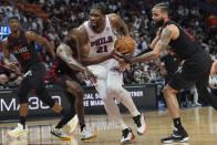 Philadelphia 76ers center Joel Embiid (21) breaks away from Miami Heat forward Haywood Highsmith and forward Caleb Martin during the first half of an NBA basketball game, Thursday, April 4, 2024, in Miami. (AP Photo/Marta Lavandier)