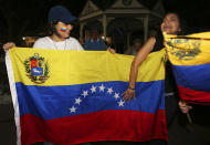 Katiry Ochoa, left, and Yalitza Lozano hold a flag from Venezuela, as they protest against Venezuelan President Nicolas Maduro with about 150 other people on the Ocala Downtown Square in Ocala, Fla., Wednesday, Jan. 23, 2019. The protestors in Ocala joined thousands of Venezuelans who took to the streets in Caracas, Venezuela, Wednesday, answering the opposition's call for a nationwide protest to rid Maduro from the office. (Bruce Ackerman/Star-Banner via AP)