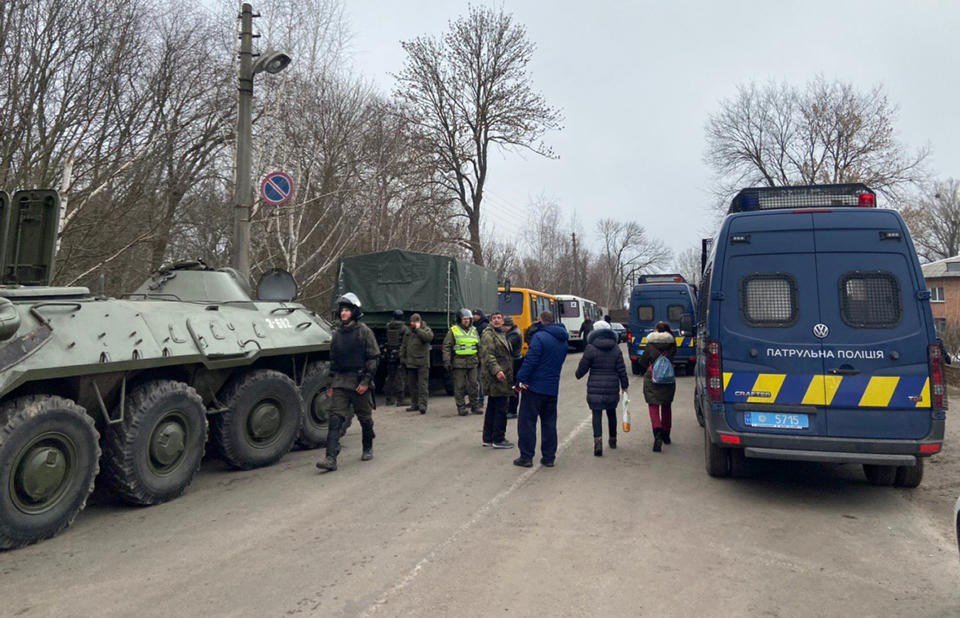 Ukrainian police gather to block protesters who planed to stop busses with passengers from the Ukrainian aircraft chartered by the Ukrainian government for evacuation from the Chinese city of Wuhan, outside Novi Sarzhany village, Ukraine, Thursday, Feb. 20, 2020. Several hundred residents in Ukraine's Poltava region protested to stop officials from quarantining the evacuees in their village because they feared becoming infected. Demonstrators put up road blocks and burned tires, while Ukrainian media reported that there were clashes with police, and more than 10 people were detained. (AP Photo)