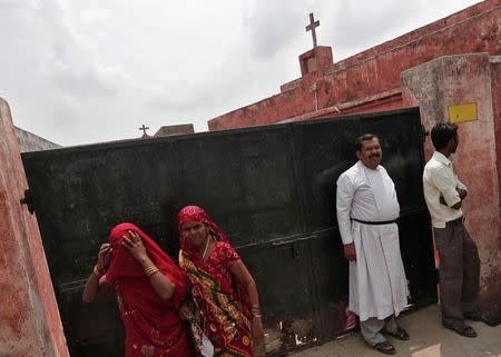 A Christian priest (2nd R) stands outside a church along with other people at Hasayan town in the northern Indian state of Uttar Pradesh August 29, 2014. REUTERS/Adnan Abidi