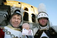 Giovanni y Maurizio, padre e hijo dedicados a entretener turistas en el Coliseo de Roma, muestran su primer pago en euros el 1 de enero de 2002 (AFP/ALBERTO PIZZOLI)