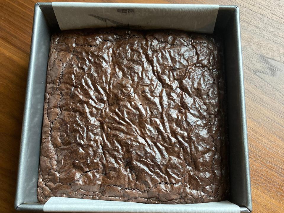 Dark-brown brownies in a square pan on a wooden table