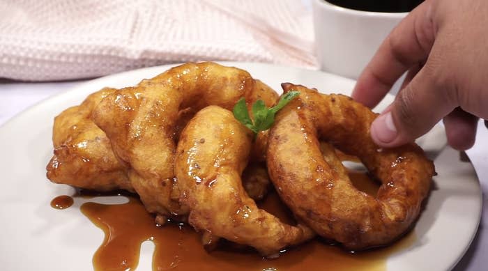 Four picarones drizzled in syrup on a plate