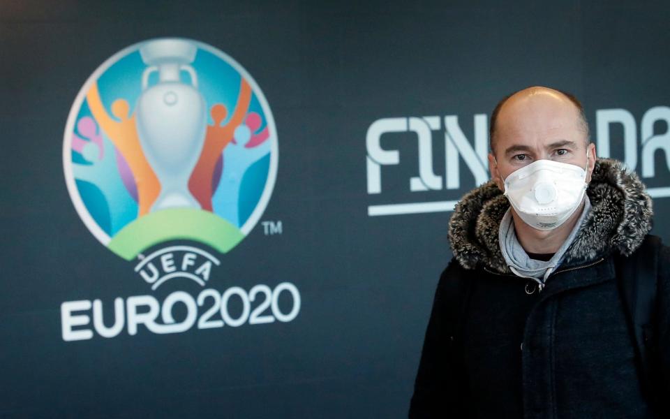 A passenger wearing a protective mask passes by a UEFA EURO 2020 banner - SHUTTERSTOCK