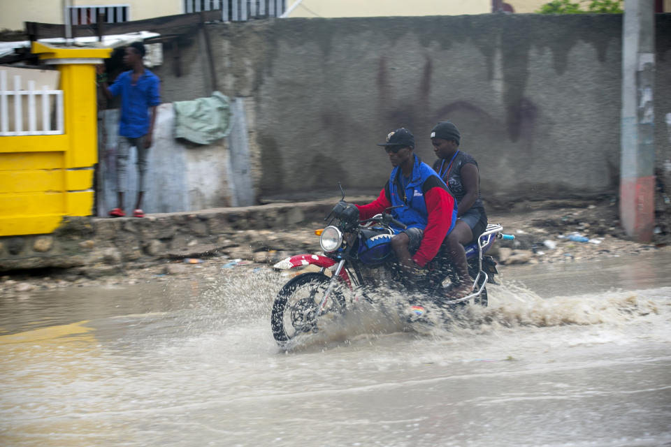 A moto-taxi driver moves through a street flooded by rain brought by the outer bands of Hurricane Isaias, in the Tabarre district of Port-au-Prince, Haiti, early Friday, July 31, 2020. Isaias kept on a path early Friday toward the U.S. East Coast as it approached the Bahamas. (AP Photo/Dieu Nalio Chery)