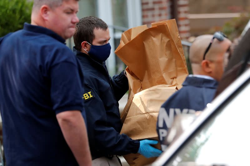 FBI officer removes evidence bags from a house, where police say bomb-making materials were found in New York