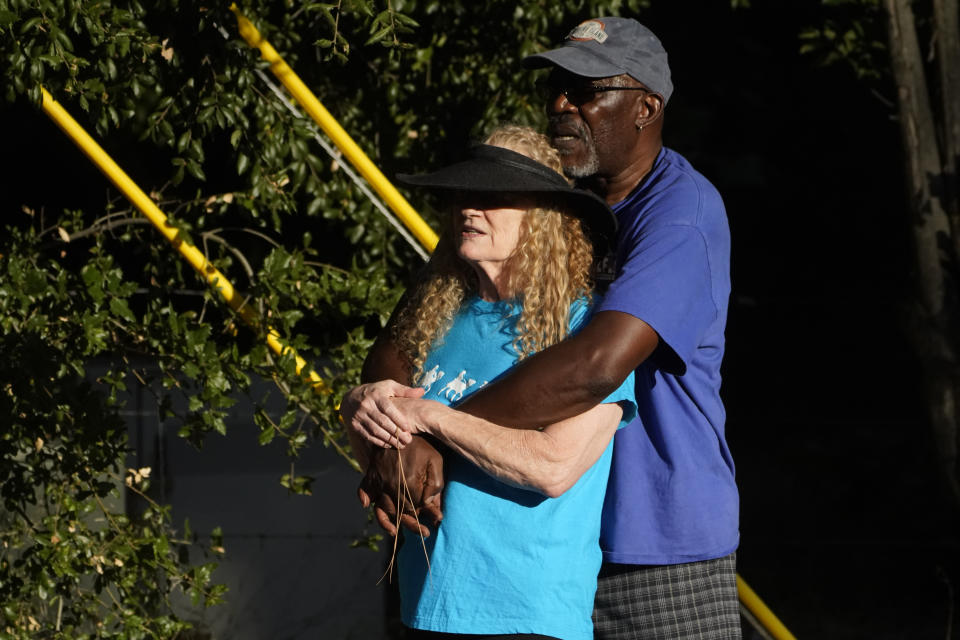Partners Susan Simmons and Jeff Carter who reside up the hill from the Cook's Corner bar look at law enforcement personnel staged at the scene of a mass shooting at Cook's Corner, Thursday, Aug. 24, 2023, in Trabuco Canyon, Calif. (AP Photo/Damian Dovarganes)