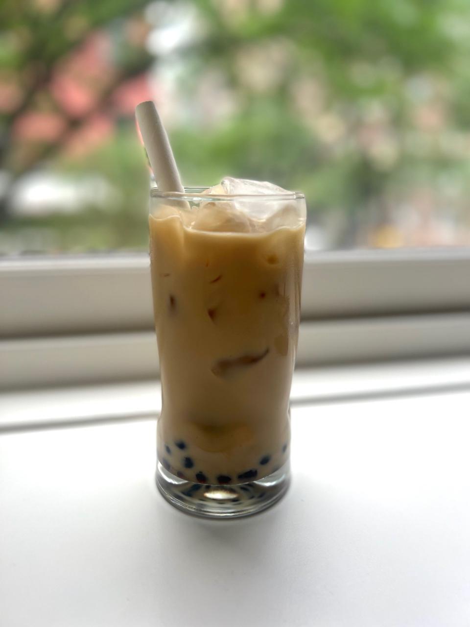 A glass of boba tea on a windowsill.