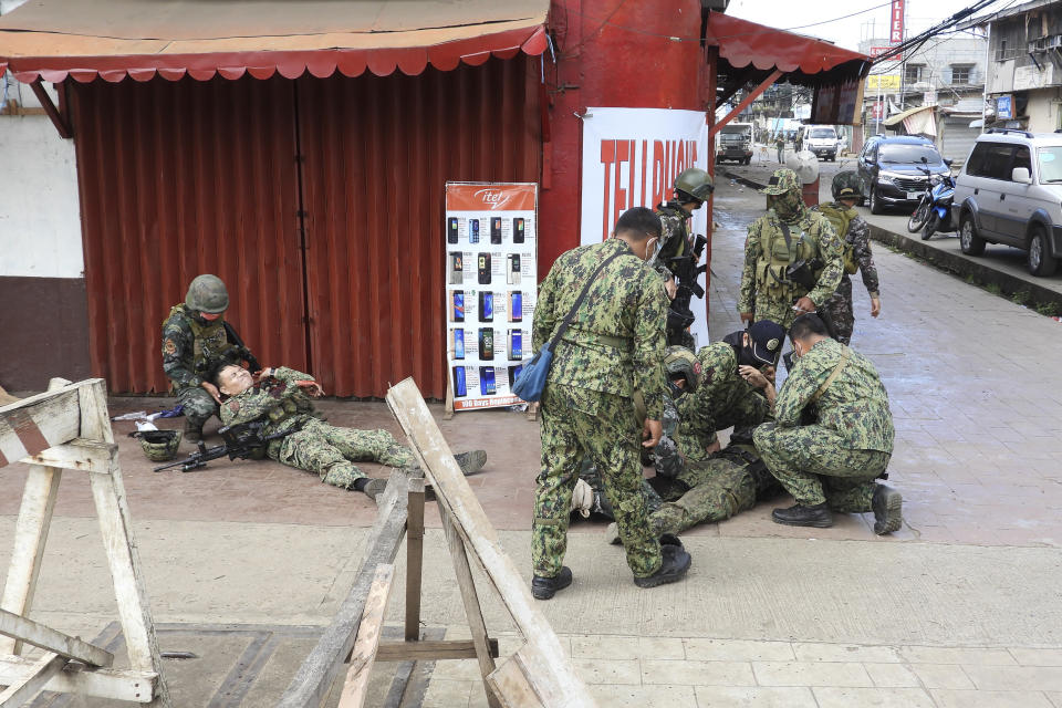 Police attend to their injured at a site of an explosion in the town of Jolo, Sulu province southern Philippines on Monday Aug. 24, 2020. Bombs exploded in a southern Philippine town Monday, killing several soldiers and wounding other military personnel and civilians despite extra tight security due to threats from Abu Sayyaf militants. (AP Photo/Nickee Butlangan)