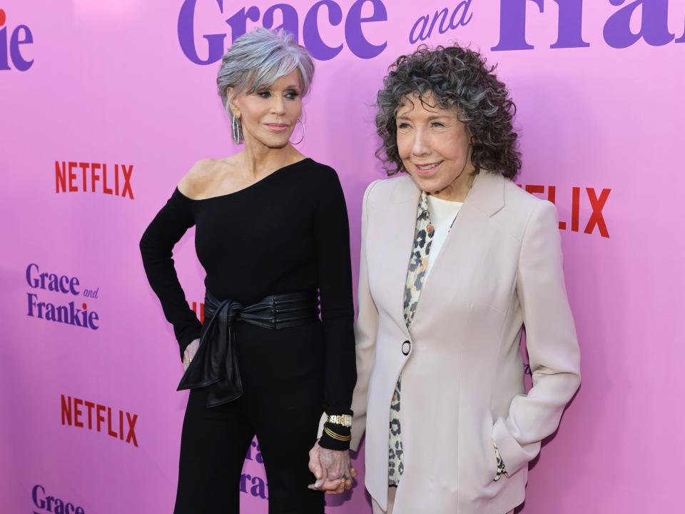 Jane smiling at Lily and the pair holding hands in front of a purple backdrop.