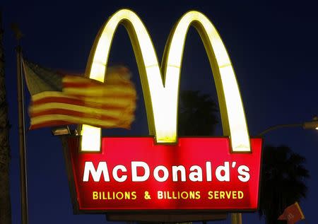 A U.S. flag flutters in the wind in front of a sign for a McDonald's restaurant in Los Angeles in this April 4, 2011 file photo. REUTERS/Mario Anzuoni/Files