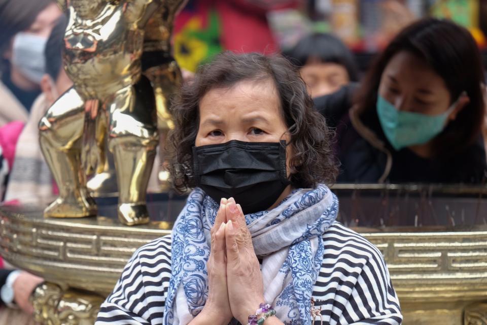 A woman wearing a protective mask prays at the Lungshan temple during the fourth day of the Lunar New year of the Rat in Taipei in January 28, 2020. - Taiwan has uncovered five cases of the deadly coronavirus so far, the latest a Taiwanese woman in her 50s who was working in Wuhan and flew to the island on January 20. The virus, which can cause a pneumonia-like acute respiratory infection, has in a matter of weeks killed more 106 people and infected more than 4,000 in China, while cases have been identified in more than a dozen other countries. (Photo by Sam Yeh / AFP) (Photo by SAM YEH/AFP via Getty Images)