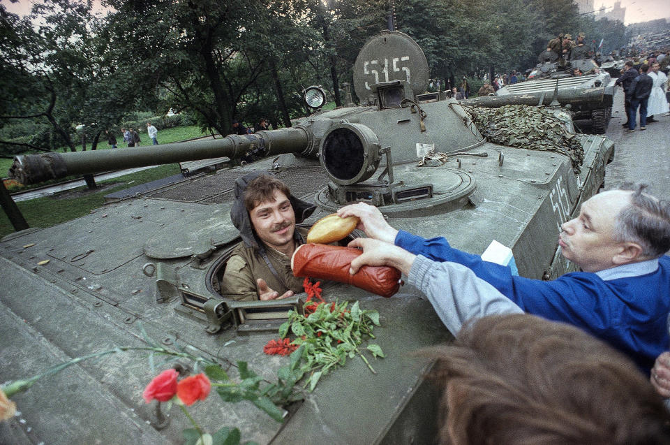 FILE - In this Wednesday, Aug. 21, 1991 file photo, appreciative muscovites hand bread, sausages and flowers to a Soviet tank's driver who helped stop the failed hardline coup in Moscow, Russia. When a group of top Communist officials ousted Soviet leader Mikhail Gorbachev 30 years ago and flooded Moscow with tanks, the world held its breath, fearing a rollback on liberal reforms and a return to the Cold War confrontation. But the August 1991 coup collapsed in just three days, precipitating the breakup of the Soviet Union that plotters said they were trying to prevent.(AP Photo/Czarek Sokolowski, File)