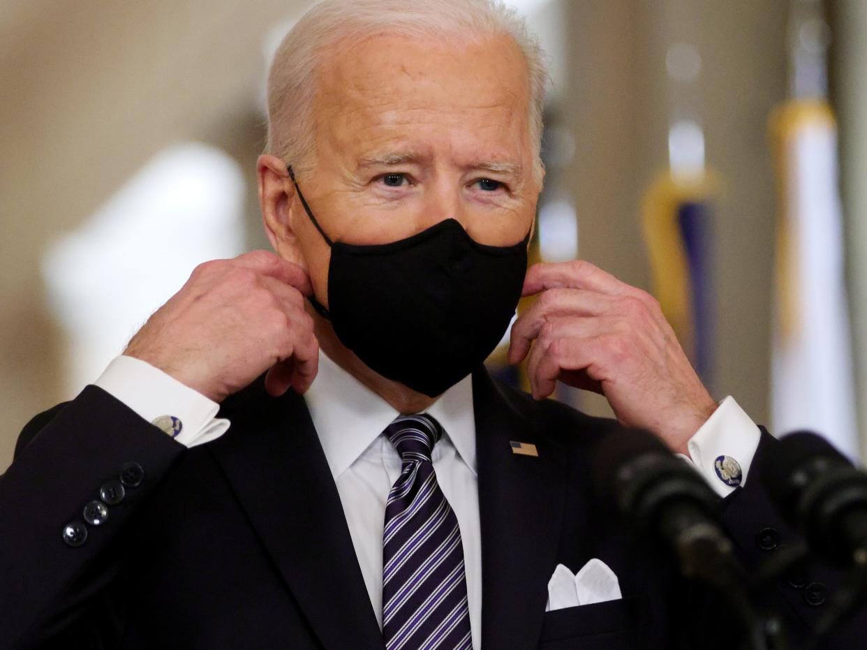 <p>President Joe Biden takes off his mask before delivering a primetime address to the nation from the East Room of the White House on 11 March 2021 in Washington, DC</p> ((Getty Images))