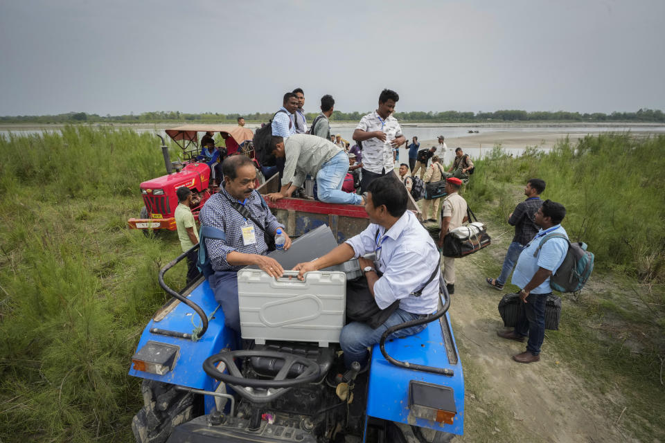 Polling officials carrying electronic voting machines and security personnel board on a tractor after disembarking from a boat after crossing the river Brahmaputra on the eve of parliament election at Baghmora Chapori (small island) of Majuli, India, April 18, 2024. (AP Photo/Anupam Nath)
