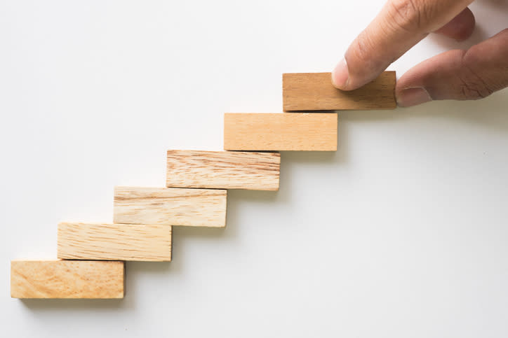 A hand building stairs out of wooden blocks.