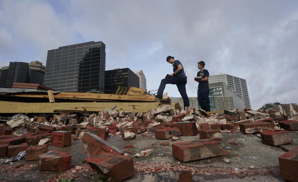 Firefighters assess damage amid fallen building debris.