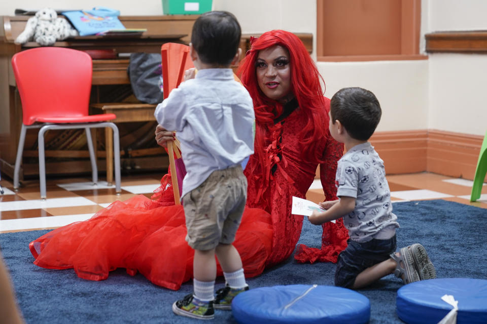 A drag queen who goes by the name Flame reads stories to children and their caretakers during a Drag Story Hour at a public library in New York, Friday, June 17, 2022. (AP Photo/Seth Wenig)