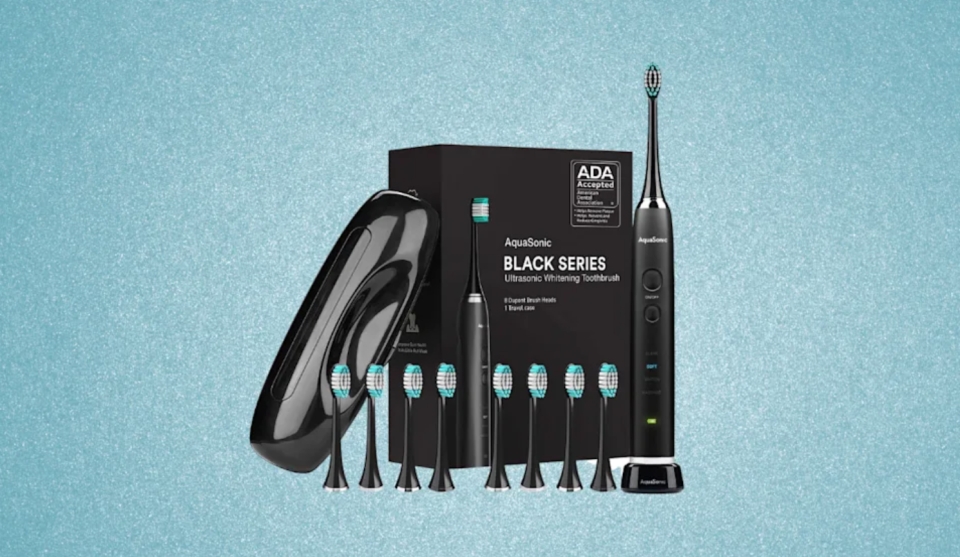 A black electric toothbrush with several replacement heads, a case, and a box with 
