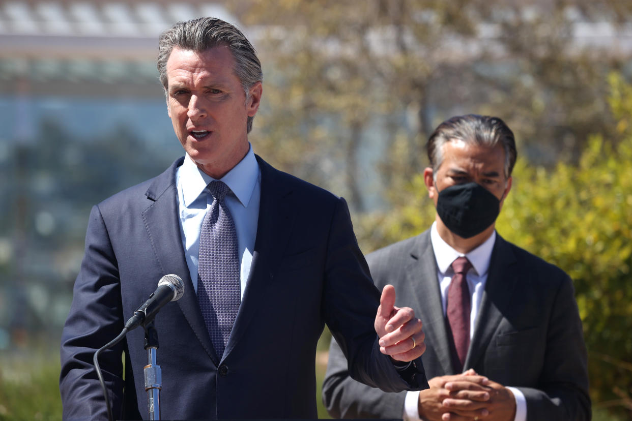 Gov. Gavin Newsom at the microphone, with Attorney General Rob Bonta, wearing a mask, standing behind him.