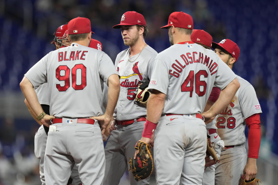 St. Louis Cardinals starting pitcher Matthew Liberatore, center, talks with pitching coach Dusty Blake (90) during the first inning of the team's baseball game against the Miami Marlins, Wednesday, July 5, 2023, in Miami. (AP Photo/Lynne Sladky)