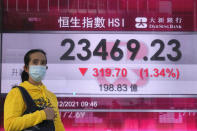 A woman wearing a face mask walks past a bank's electronic board showing the Hong Kong share index in Hong Kong, Friday, Nov. 3, 2021. Stocks were mixed in Asia on Friday after a broad rally on Wall Street as investors kept an eye on the spread of the new coronavirus variant and measures governments are taking to restrain it. (AP Photo/Kin Cheung)