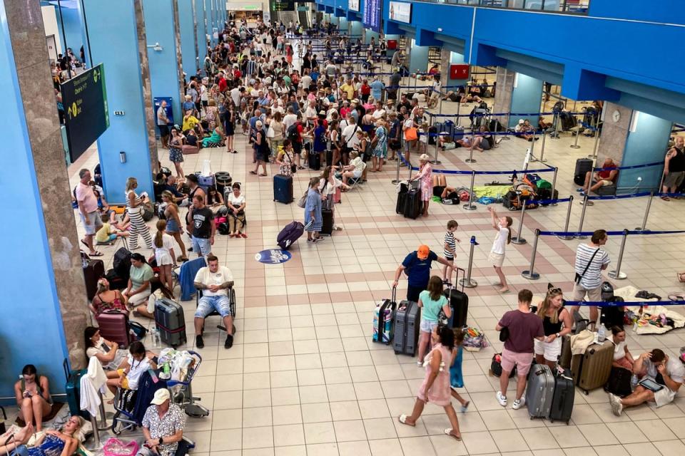 Tourists wait in the airport’s departure hall during evacuations on the Greek island of Rhodes on 23 July (AFP via Getty Images)