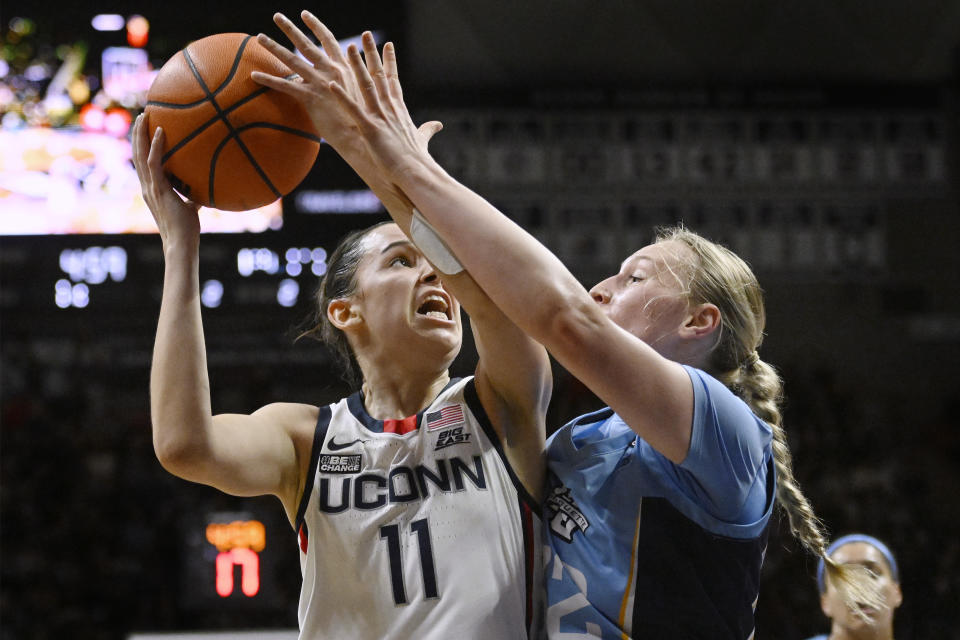Connecticut's Lou Lopez-Senechal shoots as Marquette's Liza Karlen, right, defends in the first half of an NCAA college basketball game, Saturday, Dec. 31, 2022, in Storrs, Conn. (AP Photo/Jessica Hill)