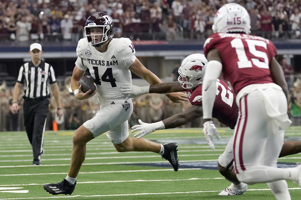 Texas A&M quarterback Max Johnson (14) runs against Arkansas linebacker Chris Paul Jr. (27) and defensive back Jaheim Singletary (15) during the first half of an NCAA college football game, Saturday, Sept. 30, 2023, in Arlington, Texas. (AP Photo/LM Otero)