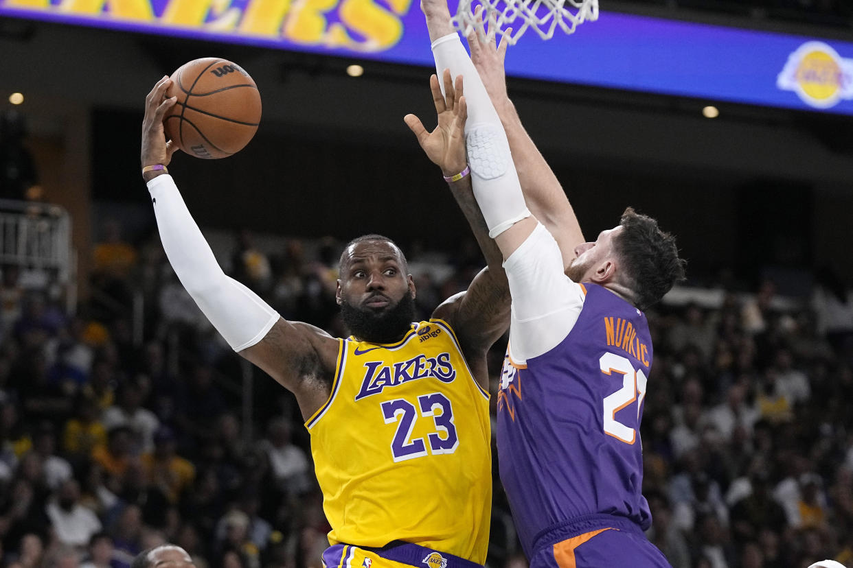 Los Angeles Lakers forward LeBron James, left, passes the ball as Phoenix Suns center Jusuf Nurkic defends during the first half of an NBA preseason basketball game Thursday, Oct. 19, 2023, in Thousand Palms, Calif. (AP Photo/Mark J. Terrill)