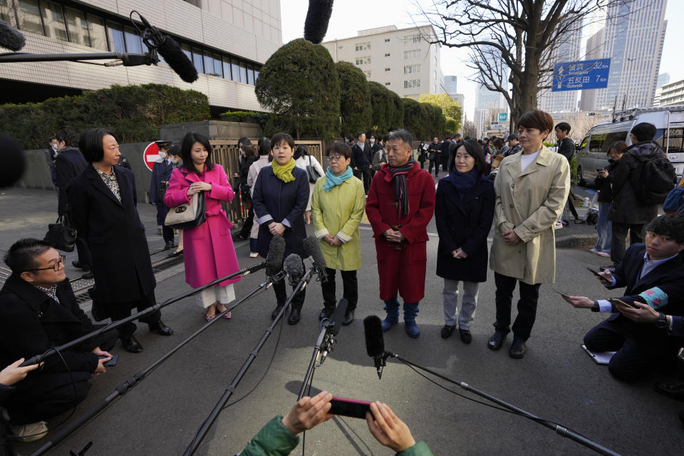 One of the plaintiffs, with a green scarf, fourth left, speaks before media members by the main entrance of the Tokyo district court before hearing the ruling regarding LGBTQ+ marriage rights, in Tokyo, Thursday, March 14, 2024. The Japanese court on Thursday ruled that not allowing same-sex couples the same marital benefits as heterosexuals violates their fundamental right to have a family, but the current civil law did not take into consideration sexual diversity and is not clearly unconstitutional, a partial victory for Japan's LGBTQ+ community calling for equal marriage rights.(AP Photo/Hiro Komae)