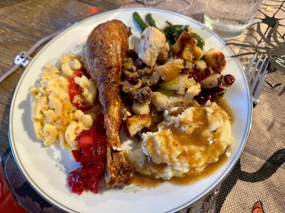 A plate of turkey, mac and cheese, cranberry sauce, mashed potatoes with gravy, and stuffing