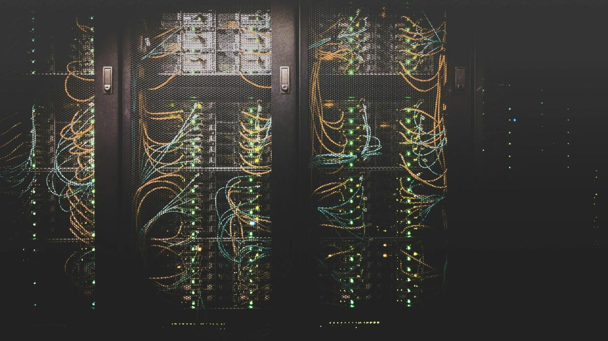  Data servers with colourful wires inside a meshed metal cupboard. 