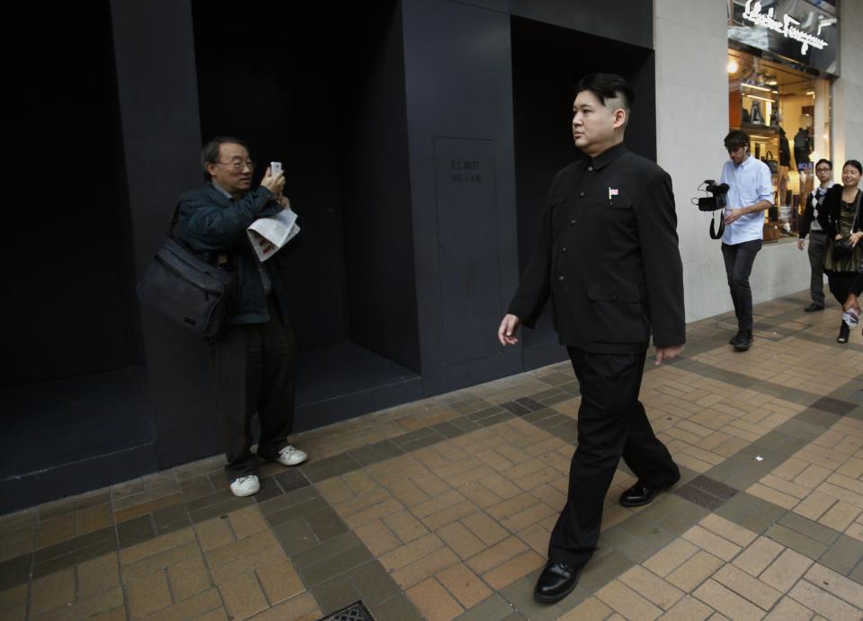 A man takes a photo of Howard while he appears as a Kim Jong-un lookalike on a street at Hong Kong's Tsim Sha Tsui shopping district