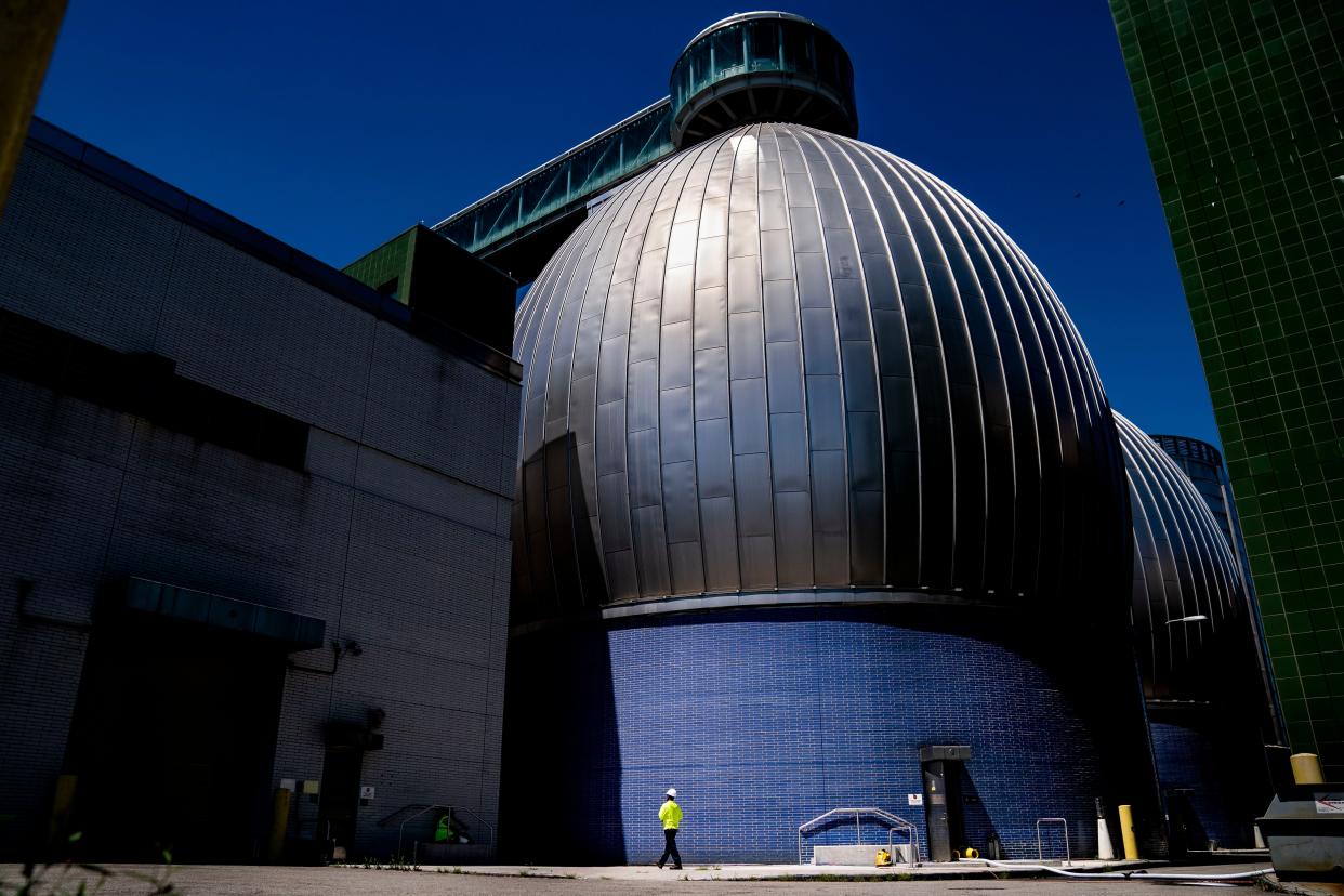 A worker walks alongside the Newtown Creek Wastewater Treatment Plant's array of digester eggs Friday in Greenpoint, Brooklyn. Health officials say the virus that causes polio has been detected in New York City's wastewater weeks after a case of polio was identified north of the city. 