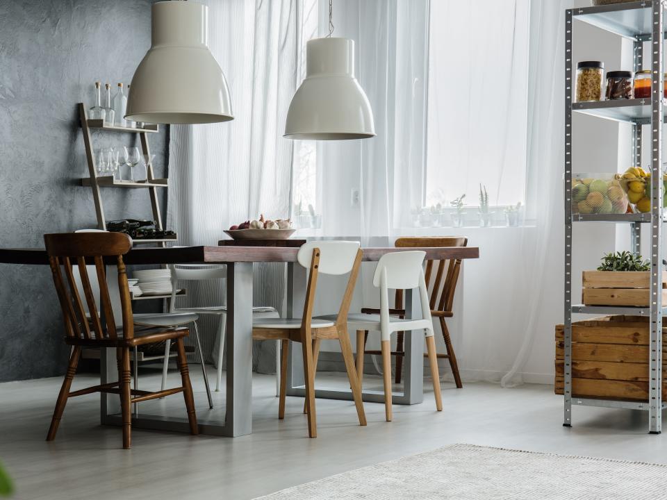 A dining table in a gray room with an array of mismatched chairs