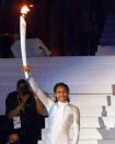<p>Australian sporting icon Cathy Freeman smiles as she holds up high the Olympic torch before lighting the Olympic cauldron.</p>