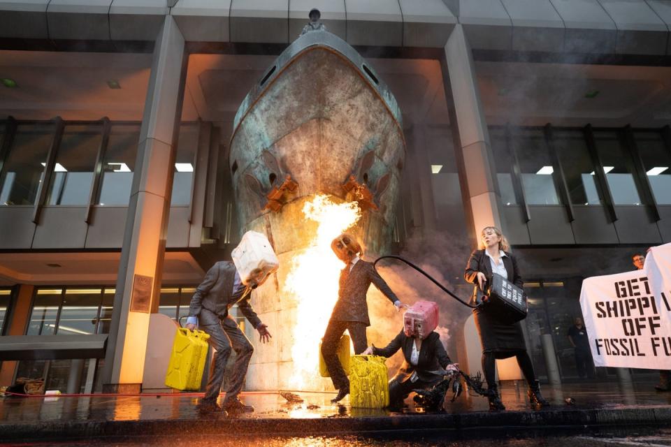 21 novembre 2022 : des militants d'Ocean Rebellion manifestent en vomissant du faux pétrole et en provoquant un incendie lors d'une manifestation devant l'Organisation maritime internationale (OMI), dans le centre de Londres, qui coïncide avec une série d'actions plus larges visant à couper les liens avec l'industrie des combustibles fossiles (PA )