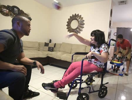 Alma Rivera, 39, plays with her brother-in-law Isuain Luna (L) while her nephews Gabriel Baez, 14, and Ixuan Luna, 10 months., watch at their home in Kissimmee, Florida, U.S. December 2, 2016. REUTERS/Phelan Ebenhack