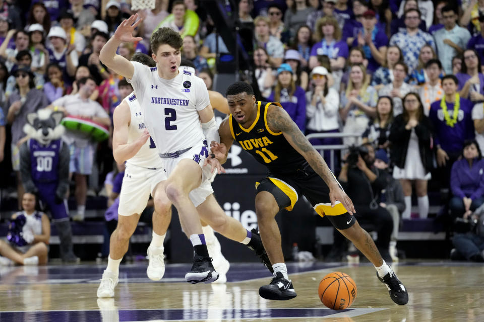 Iowa guard Tony Perkins, right, drives as Northwestern forward Nick Martinelli guards during the first half of an NCAA college basketball game in Evanston, Ill., Sunday, Feb. 19, 2023. (AP Photo/Nam Y. Huh)