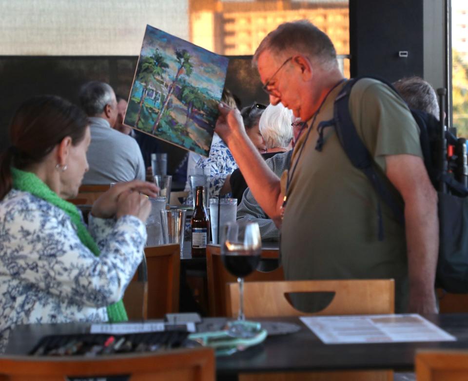Artist Preston King moves through the crowd at the Avanu on Flagler with his work, Tuesday, Oct. 17, 2023, during the New Smyrna Beach Plein Air Paint Out.