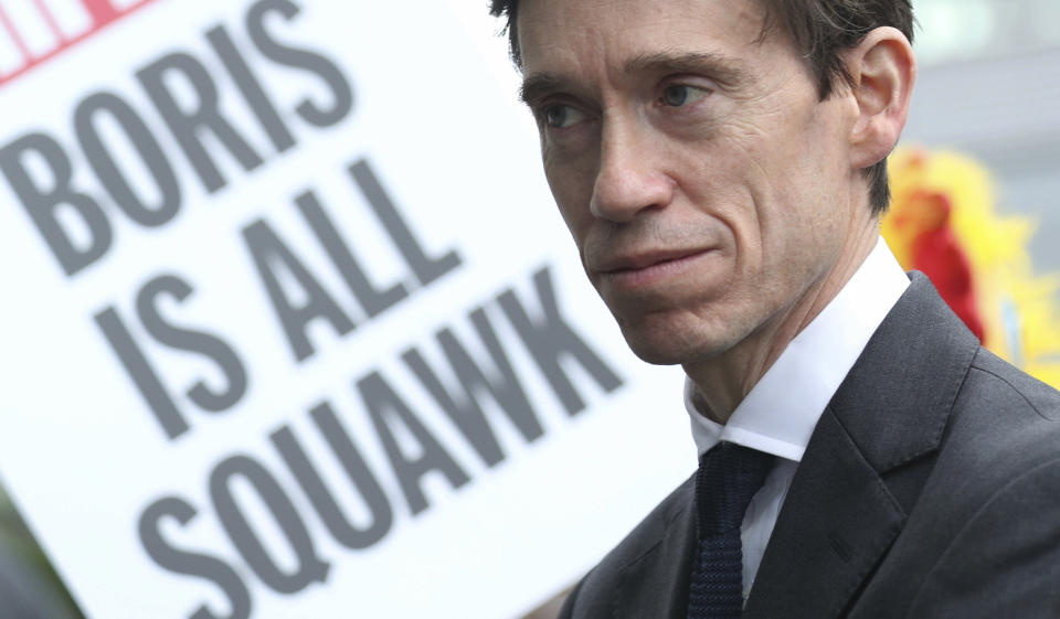 A poster is brandished during a public demonstration as Conservative party leadership contender Rory Stewart arrives at the television studios ahead of a scheduled live television debate for the Conservative Party leadership candidates, in London, Sunday June 16, 2019. Five out of the six candidates will appear in the first TV debate, with Boris Johnson declining to take part, although other candidates accuse him of trying to avoid scrutiny. (Yui Mok/PA via AP)