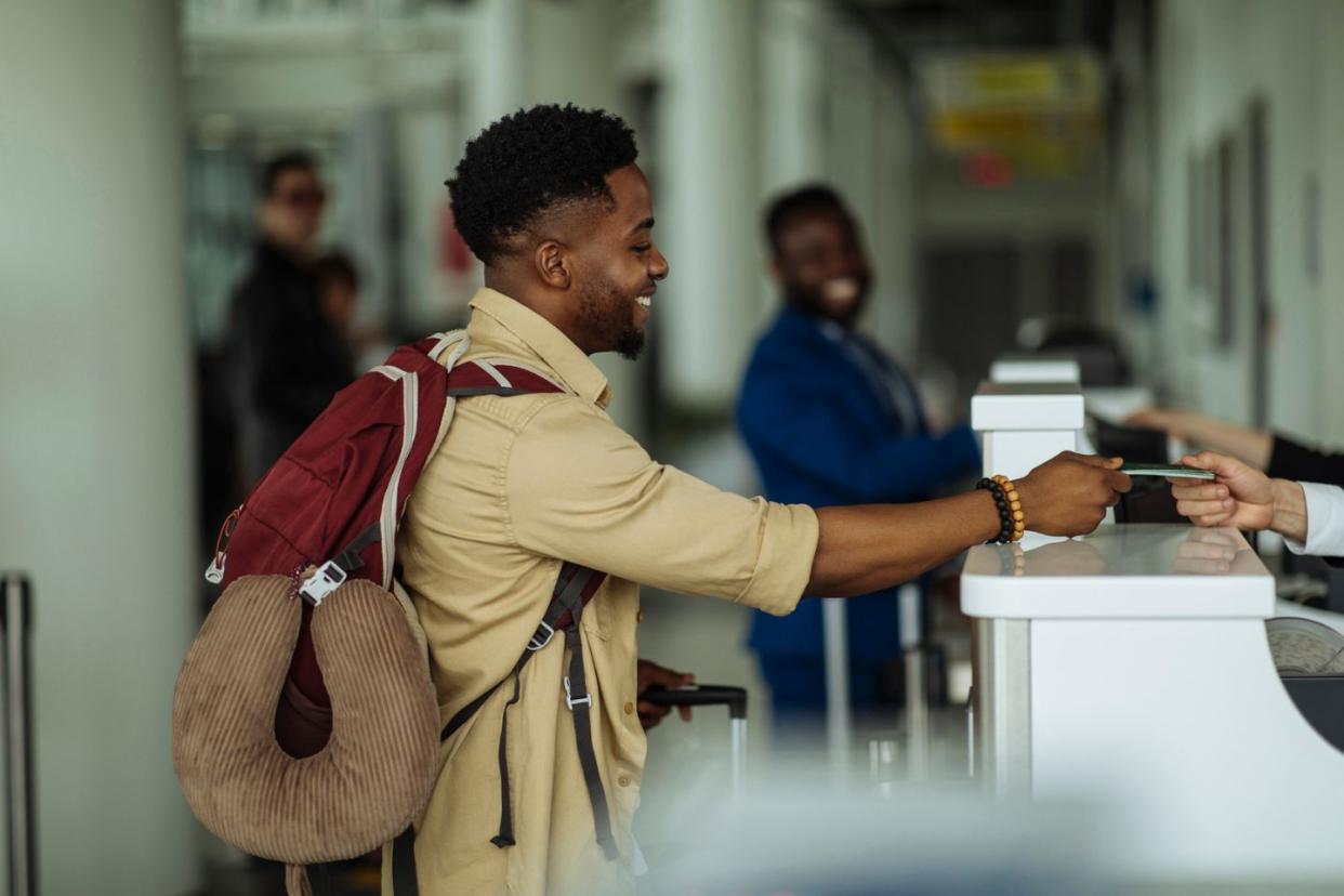 man checking in to flight at airport gate counter