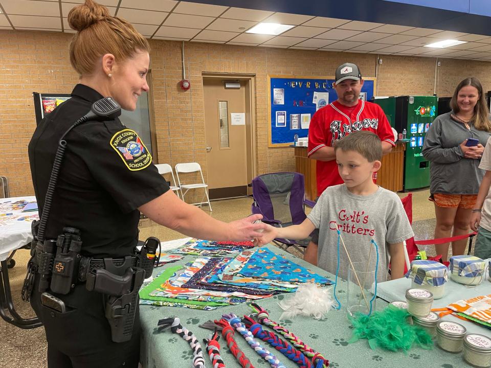 Knox County Schools officer Jenn Desautels supports the cause buying a candle from Colt Daniels, 10, at the fourth annual Community Bazaar at Karns High School Saturday, April 30, 2022.
