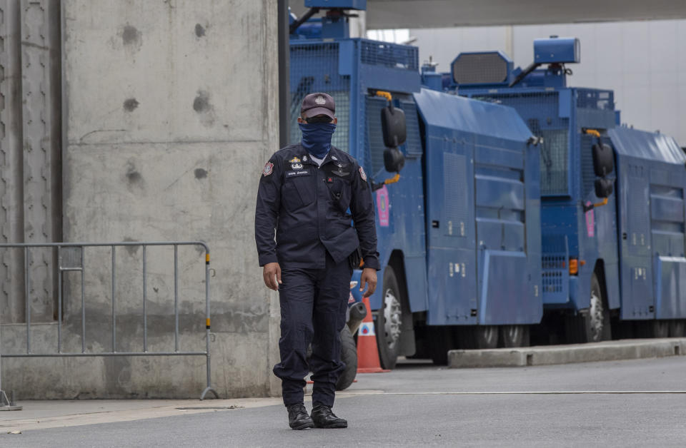 A police officer stands guard at the entrance to the Parliament building, lined with anti-riot vehicles ahead of a pro-democracy rally outside in Bangkok, Thailand, Thursday, Sept. 24, 2020. Lawmakers in Thailand are expected to vote Thursday on six proposed amendments to the constitution, as protesters supporting pro-democratic charter reforms gathered outside the parliament building. (AP Photo/Gemunu Amarasinghe)