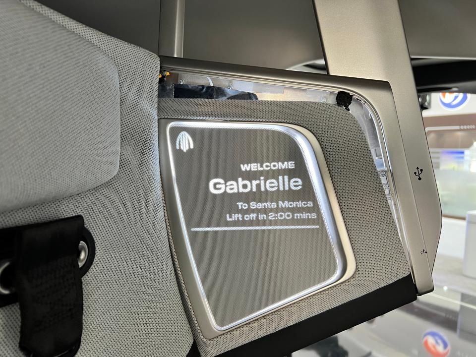 An LED display on the headrest of an Archer Midnight eVTOL says: Welcome Gabrielle / To Santa Monica / Lift of in 2:00 mins