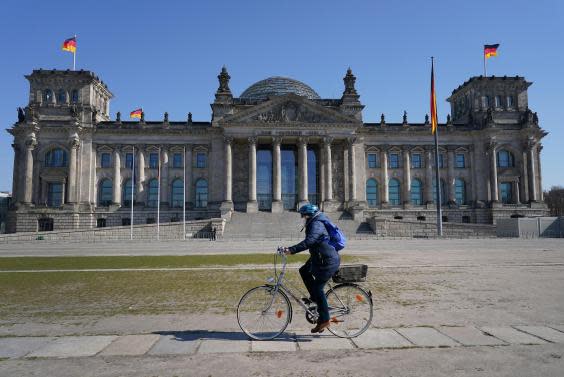 A woman rides a bicycle past the Reichstag, Berlin (Getty)